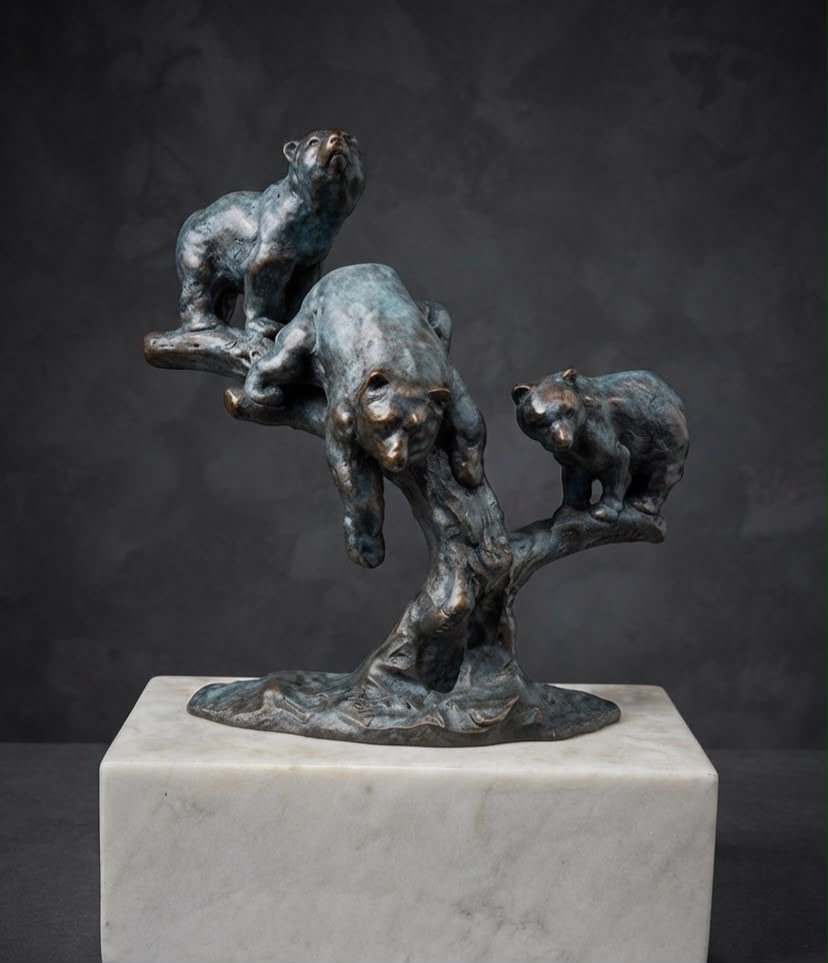 Bronze sculpture of three bear's playing on a tree.